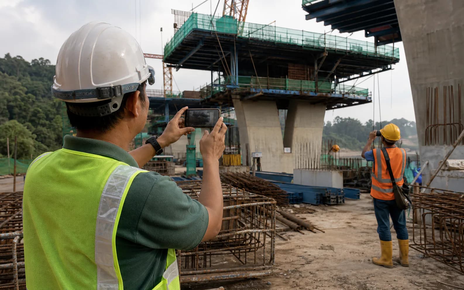 Malaysian site supervisors taking progress photographs at an active engineering construction project